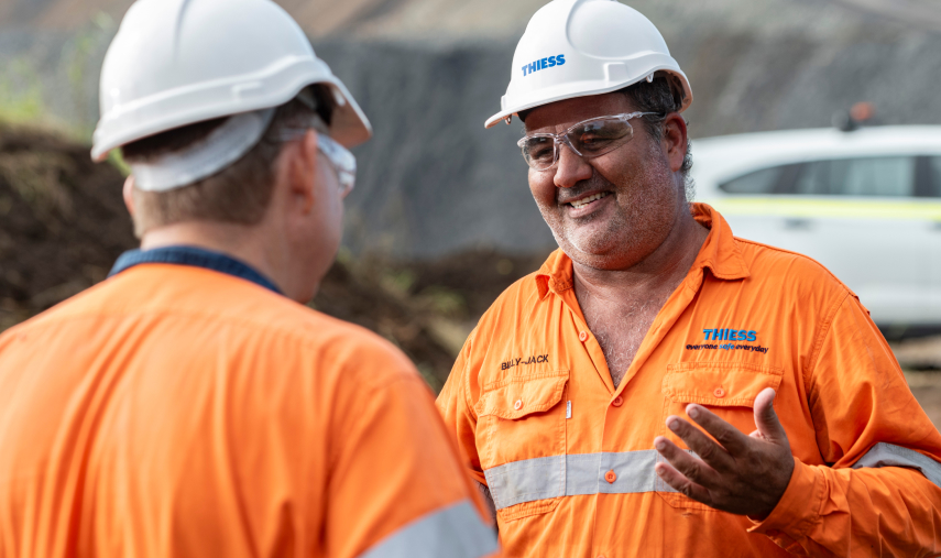 Two men in workwear smiling and talking