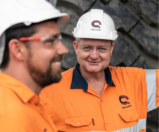 Two men in hardhats and workwear smiling
